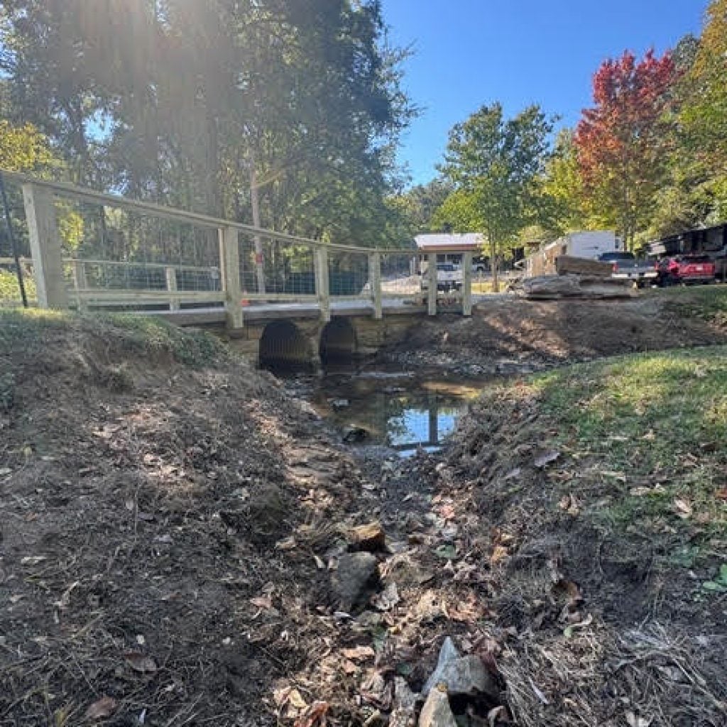 A wooden bridge crossing over a shallow stream.